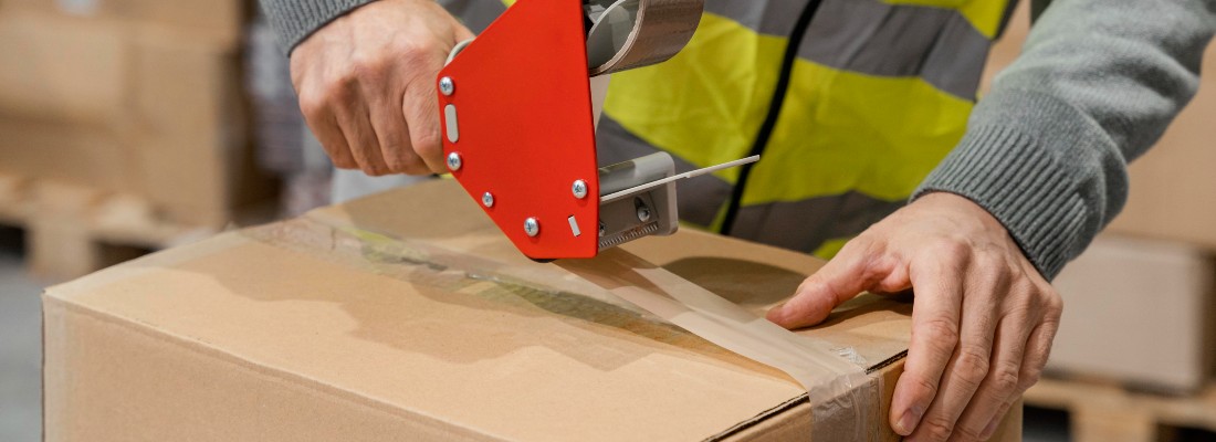 Un préparateur de commandes emballe un carton