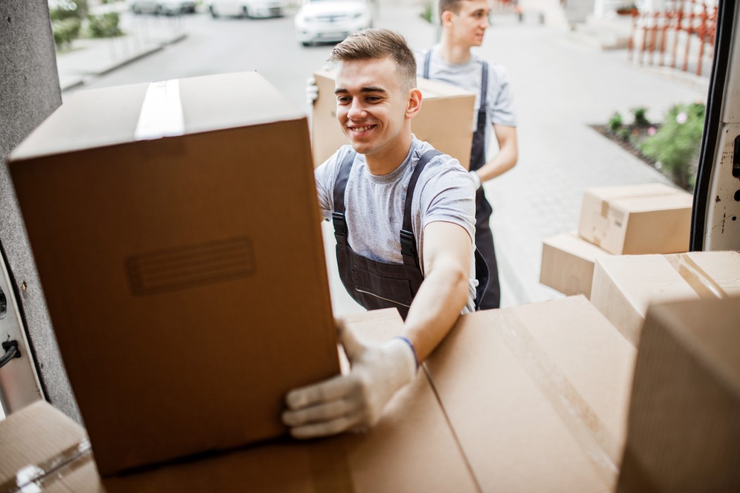 Un déménageur souriant pose un carton dans le camion