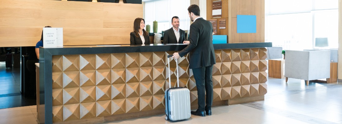 Un touriste avec une valise se présente à la réception d'un hôtel.