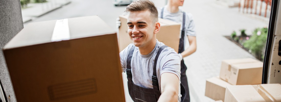 Un déménageur souriant pose un carton dans le camion