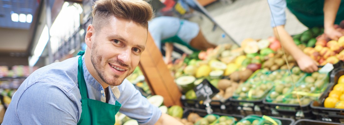 Un homme travaille au rayons fruits et légumes dans un supermarché