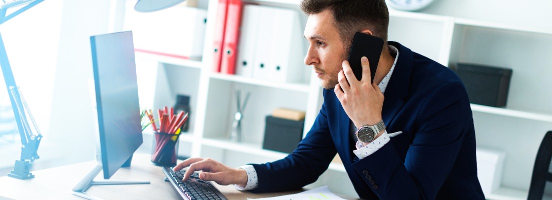 Un homme au téléphone devant son ordinateur